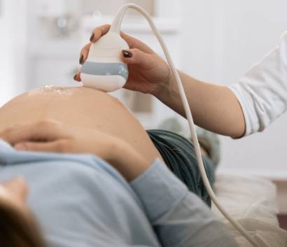 Healthcare professional performing an ultrasound scan on a pregnant woman's abdomen in a clinical setting